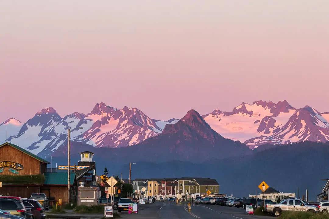 Purple snowcapped mountains at sunset with buildings in the foreground