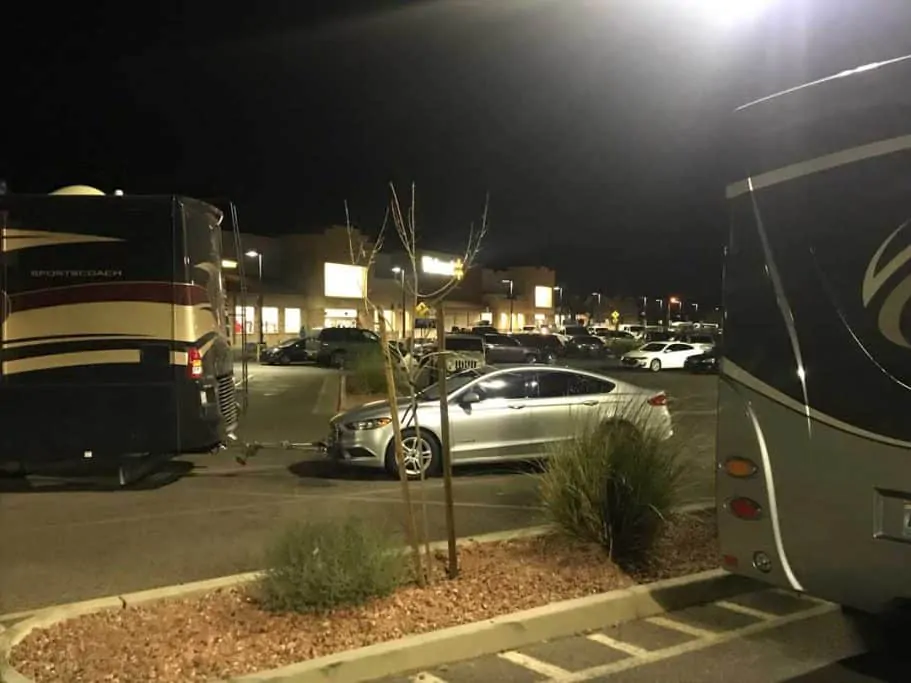 RV towing a car parked sideways across many parking spaces