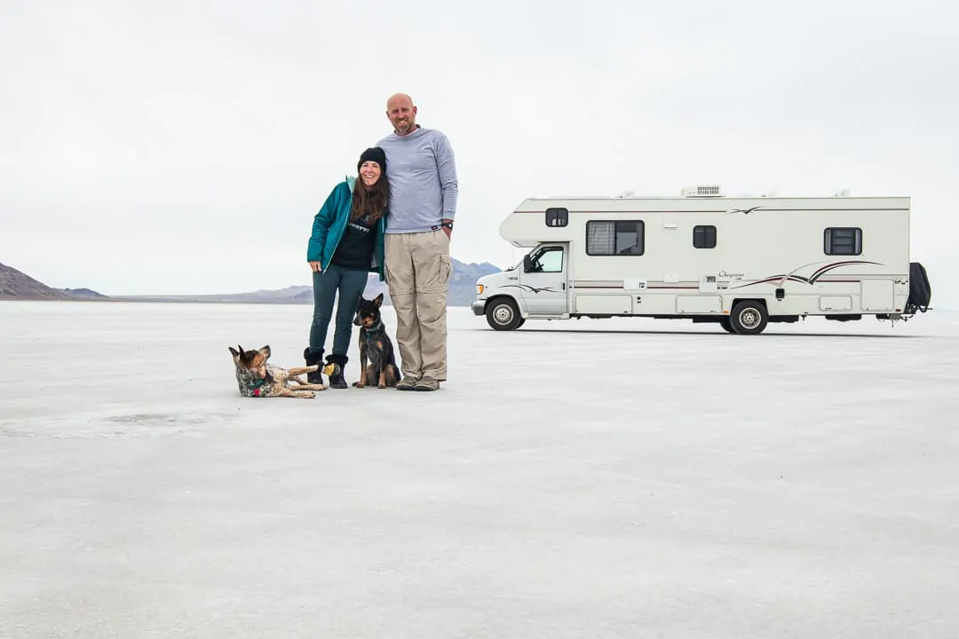 Couple posing with their dogs in front of their RV on the Bonneville Salt Flats