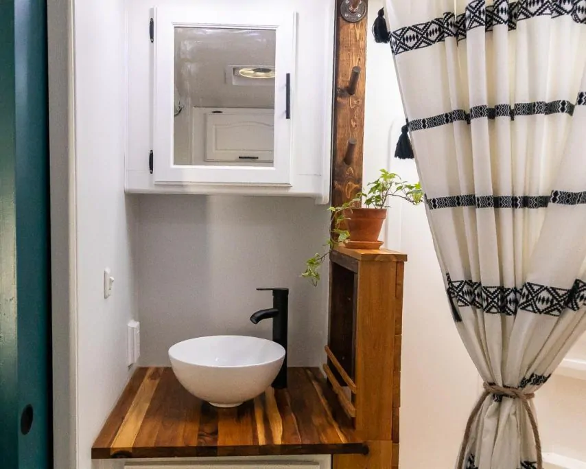 Vessel sink and faucet on butcher block countertop in an RV bathroom